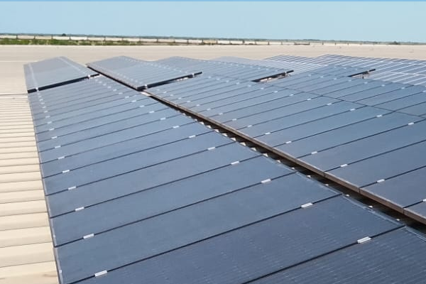 Planta industrial con un campo de paneles solares adyacente